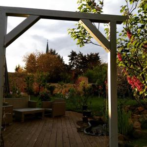 a wooden deck with a pergola in a garden at Fliederhof in Michendorf