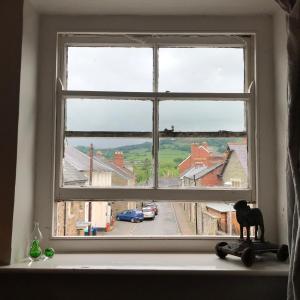 a cat statue sitting on a window sill looking out at Half Moon House top flat in Hay-on-Wye