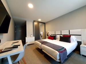 Un dormitorio con una cama grande y un escritorio y aaptop en Apartahotel 5dos5, en Oviedo