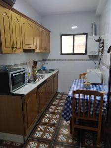 a kitchen with wooden cabinets and a sink and a table at Casa Rural San Antonio in La Puebla de los Infantes