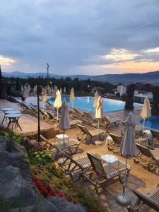 a group of chairs and tables with umbrellas next to a pool at Vikeya Guest House in Sapareva Banya