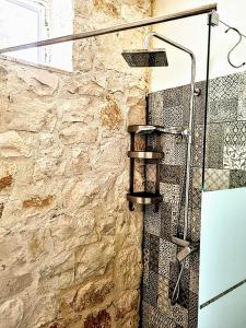 a shower in a bathroom with a stone wall at Trullo Oasi Veronica in Ostuni +21 photos