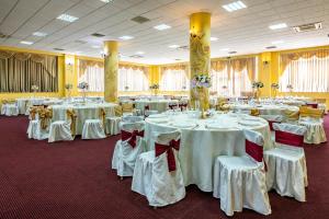 - une salle de banquet avec des tables blanches, des chaises et des bows dans l'établissement Motel Dasiana, à Târgu Jiu