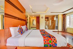 a bedroom with a large bed with a wooden headboard at FabHotel Abirami Grand Inn in Kodaikānāl