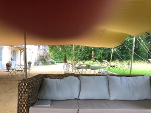 um sofá debaixo de um guarda-chuva amarelo num quintal em Domaine du Plessis em Le Plessis-Luzarches