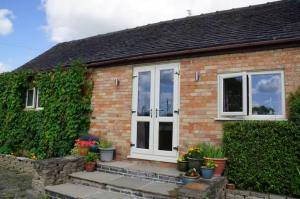 a brick house with a white door and plants at Stag Cottage in Ilkeston