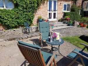 a patio with two chairs and a table with a bottle of wine at Stag Cottage in Ilkeston