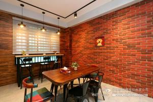a dining room with a brick wall and a wooden table at 啾吉民宿河畔館 宜蘭五結8到14人包棟民宿 in Yilan City