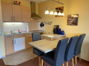 una cucina con un tavolo di legno e sedie blu di App 510 Panoramic Hohegeiß mit Fernblick a Braunlage