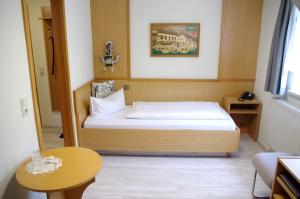 Hotel Gasthof zum Walfisch في كلينغنتال: غرفة نوم صغيرة مع سرير وطاولة