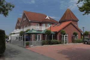 a large brick building with a turret on a street at Landhotel Esen in Neuharlingersiel