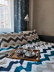 a tray with cups and saucers on a bed at The good stay in Šiauliai