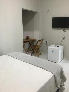 a room with a bed and a table and a television at Serra Village Hotel in Ubajara