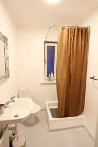 ein Bad mit einem Duschvorhang und einem Waschbecken in der Unterkunft Modern apartment near beach, marina & city centre in Tórshavn