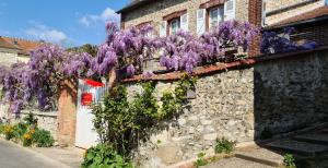 um edifício com glicínias roxas ao lado em Le petit nid d'aigle - Giverny em Giverny