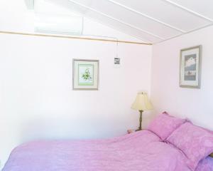 Cama morada en habitación blanca con lámpara en Motel Rideau, en Brossard