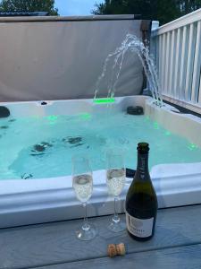 a bottle of wine and two wine glasses in front of a hot tub at Graceland Lodge with Hot Tub in Barmby on the Moor