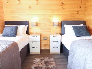 two beds in a room with two lamps on tables at Bacheiddon Log Cabin in Machynlleth +26 photos