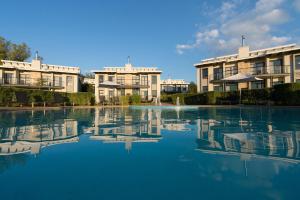 uma piscina de água em frente a alguns edifícios em The Fairway Hotel, Spa & Golf Resort em Joanesburgo