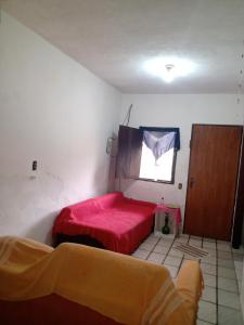 a bedroom with a red bed and a window at Hostel Casa Shamballa in Camburi