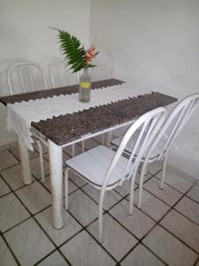 a table with white chairs and a potted plant on it at Hostel Casa Shamballa in Camburi