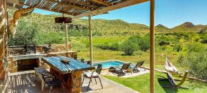 un patio con mesa, sillas y piscina en Karoo Ridge Eco-Lodges en Spring Valley