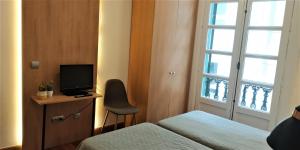 a room with two beds and a television and a window at Roquefer Bilbao by gaiarooms in Bilbao