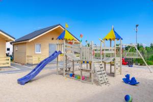 a playground with a slide and play equipment in the sand at Domki gościnne Govinda in Ustka