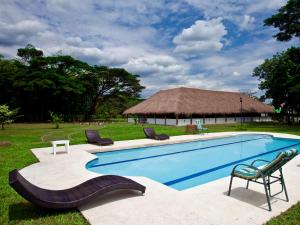 una piscina con sillas y una cabaña en Hotel Cinaruco Caney, en Villavicencio
