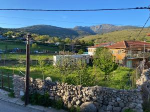 una pared de piedra frente a un pueblo con montañas en El rincón de Siete Picos, en Cercedilla