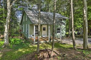 una casa verde en el bosque con árboles en Warm and Cozy Adirondacks Cabin on Otter Lake!, en Forestport