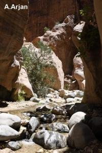 a group of rocks in a river in a canyon at Wadi Ghwere Camp مخيم وادي الغوير in Al Khuraybah