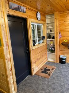 una puerta de garaje negra en una cabaña de madera con reloj en The Fishing Bear Lodge, en Ashton