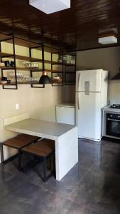 eine Küche mit einem Tisch und einem weißen Kühlschrank in der Unterkunft Casa praia fortaleza pé na areia in Ubatuba