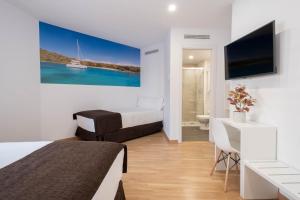 Hotel BESTPRICE Girona في جيرونا: غرفة فندقية بسريرين ومكتب وتلفزيون