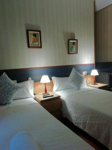 two beds in a hotel room with two lamps at Pensión San Jerónimo in San Sebastián