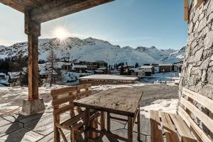 a wooden table and bench on a balcony with snow covered mountains at Alpslodge - Amelia in Arosa