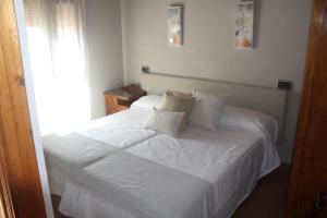 a bedroom with a white bed with white sheets and pillows at Les Casines in Luanco