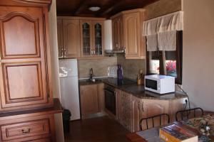 una cocina con armarios de madera y microondas en una encimera en Les Casines, en Luanco