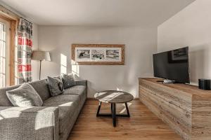 ein Wohnzimmer mit einem Sofa und einem Flachbild-TV in der Unterkunft Alpslodge - Napa in Arosa