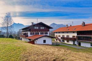 un grupo de edificios en una colina con montañas en el fondo en Gästehaus Koyerbauer Boardinghouse en Aschau im Chiemgau