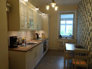 a kitchen with white cabinets and a sink and a table at Schöne Ferienwohnung in der City Königswohnung Jun in Kiel +30 photos