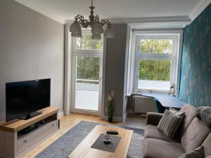 a living room with a couch and a tv and two windows at Schöne Ferienwohnung in der City Königswohnung Jun in Kiel