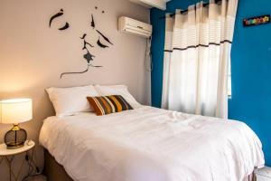 um quarto com uma cama branca e uma parede azul em CityLife Apartments in Willemstad - groundfloor 2 bedroom apartment - B em Willemstad
