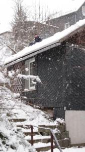 a person sitting on the roof of a house in the snow at Gasthaus Piesau - Thüringer Wald - Rennsteig in Piesau