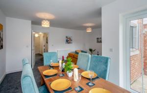 ein Esszimmer mit einem Holztisch und blauen Stühlen in der Unterkunft Luxury 3 Bed House on Private Walkway with Parking, King's Hill. in Kings Hill