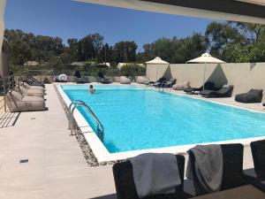 a swimming pool with chairs and a person in the water at Swans Luxury Homes in Kommeno