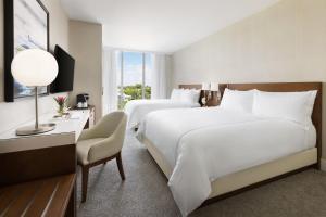 um quarto de hotel com 2 camas e uma secretária com uma cadeira em The Altair Bay Harbor Hotel em Miami Beach