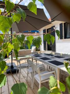 eine Terrasse mit einem Tisch, Stühlen und einem Sonnenschirm in der Unterkunft Villa du bassin -un petit coin de paradis in Andernos-les-Bains