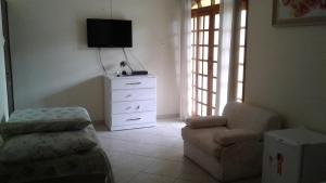 a living room with a chair and a dresser at Pousada Costa Coral in Tamandaré